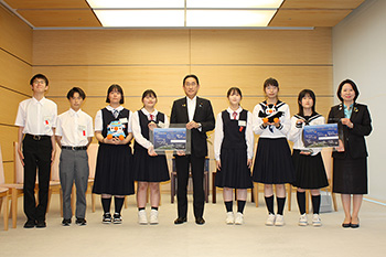 岸田内閣総理大臣が中央に立ち、その両脇に学生が数名並んでいる写真