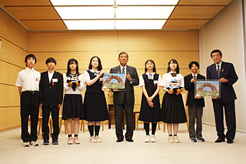 石破内閣総理大臣が中央に立ち、その両脇に学生が数名並んでいる写真