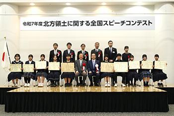 数名の大人と、賞状を持っている生徒が椅子に座っている集合写真